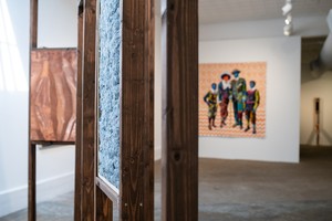 装置视图，塑造黑人的身体，前景是Kenturah Davis的木雕，背景是Bisa Butler的四个人物的彩色绘画。